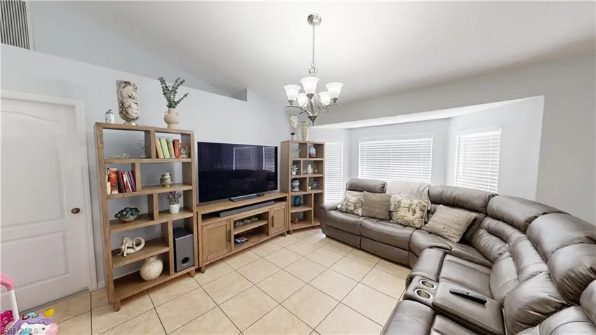 Living room featuring lofted ceiling, a chandelier, and light tile patterned flooring
