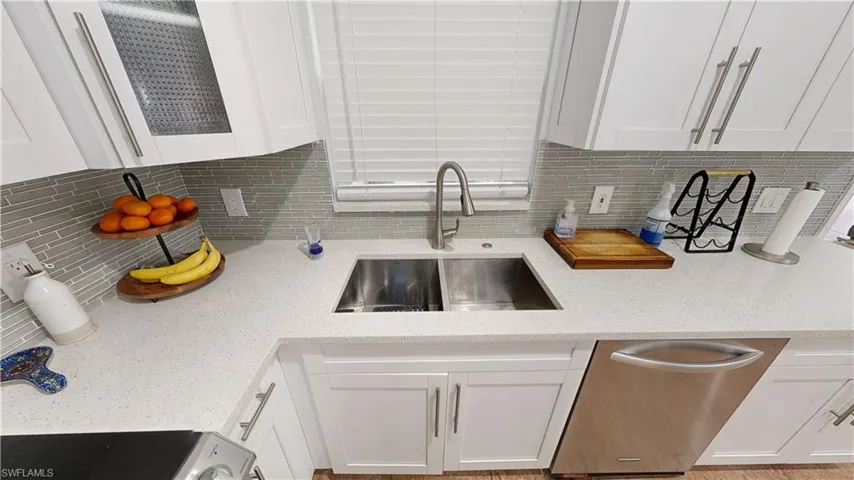 Kitchen featuring light stone countertops, sink, and white cabinets