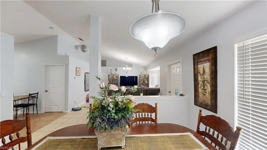 Tiled dining area with a notable chandelier and vaulted ceiling