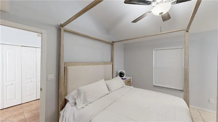 M. Bedroom featuring a closet, ceiling fan, light tile patterned floors, and vaulted ceiling