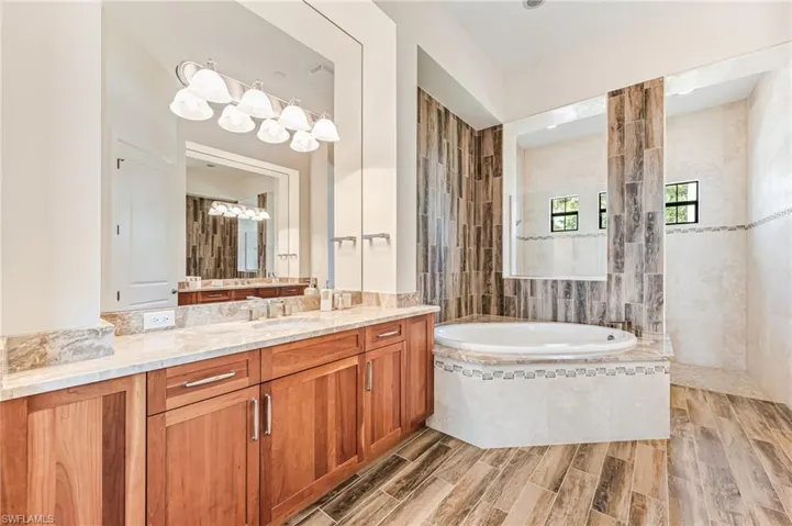 Full bathroom featuring a garden tub, vanity, wood finish floors, and a walk in shower