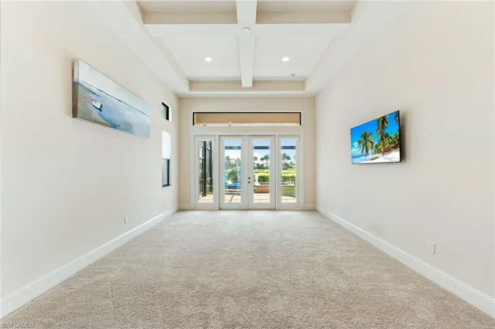 Carpeted spare room with french doors, beamed ceiling, coffered ceiling, a towering ceiling, and recessed lighting