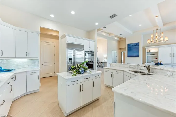 Kitchen featuring tasteful backsplash, decorative light fixtures, appliances with stainless steel finishes, light stone counters, and white cabinets