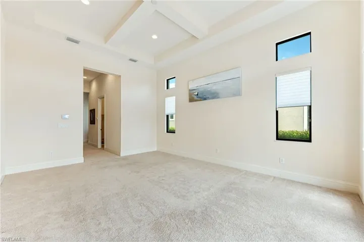 Empty room with beam ceiling, plenty of natural light, light colored carpet, coffered ceiling, and recessed lighting