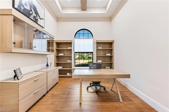 Office featuring light wood-style floors and a tray ceiling