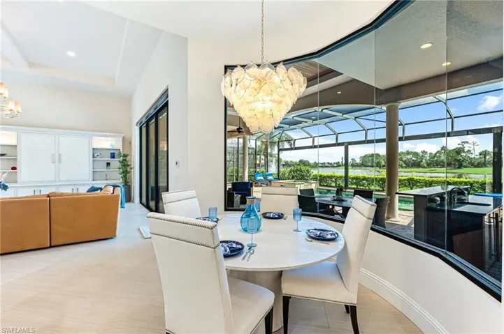 Dining room with a chandelier, a sunroom, recessed lighting, and a water view