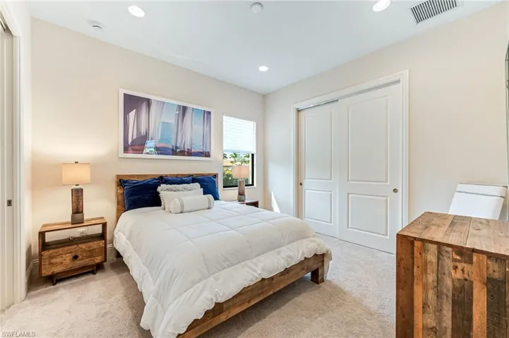 Bedroom with a closet, light carpet, and recessed lighting