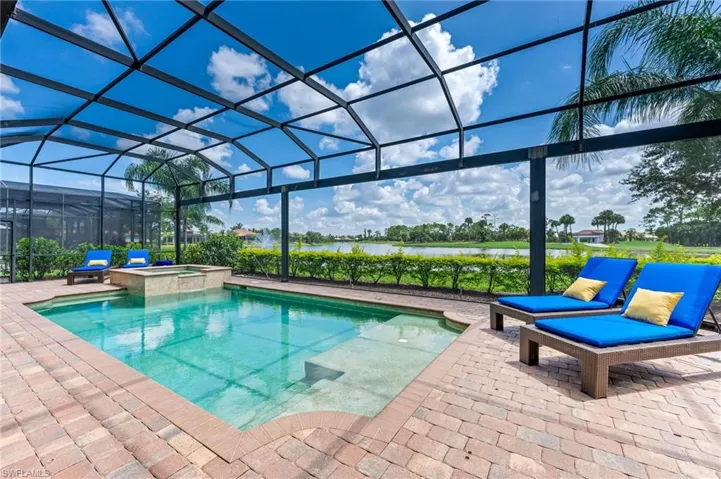 View of swimming pool featuring a lanai, a water view, a pool with connected hot tub, and a patio