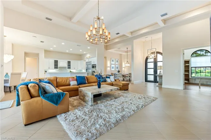 Living room featuring a chandelier, beam ceiling, light tile patterned floors, a high ceiling, and coffered ceiling