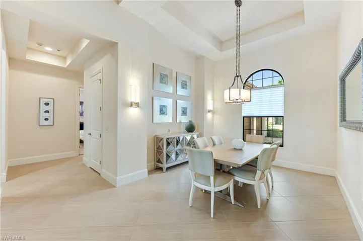 Dining space with a tray ceiling, light tile patterned flooring, and a chandelier