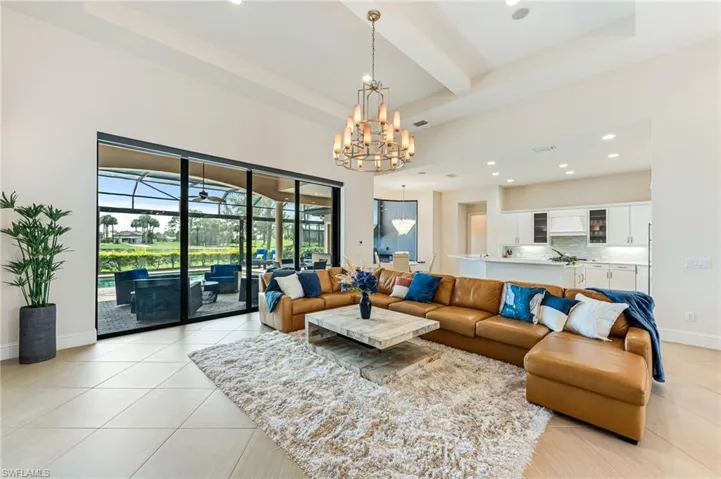 Living area with beamed ceiling, light tile patterned flooring, a sunroom, recessed lighting, and a chandelier