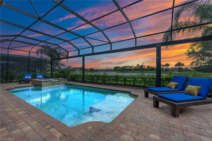 Pool at dusk featuring a lanai, a pool with connected hot tub, and a patio