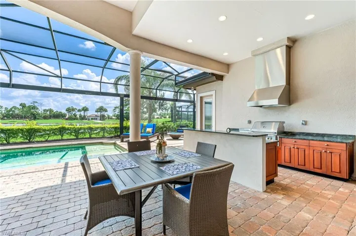 View of patio with a sunroom, outdoor dining area, exterior kitchen, a lanai, and an outdoor pool
