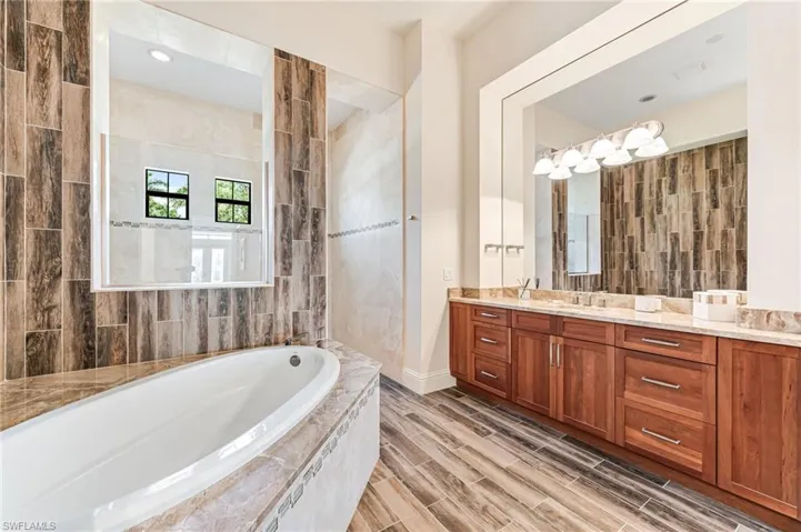 Bathroom featuring a bath, vanity, walk in shower, and wood finish floors
