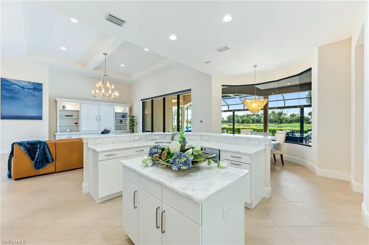 Kitchen with a chandelier, open floor plan, white cabinetry, hanging light fixtures, and light tile patterned floors