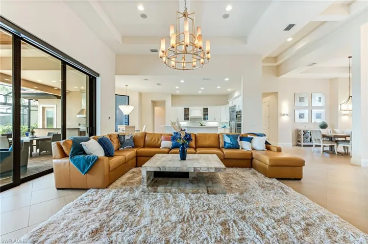 Living room featuring a chandelier, a tray ceiling, light tile patterned flooring, and recessed lighting