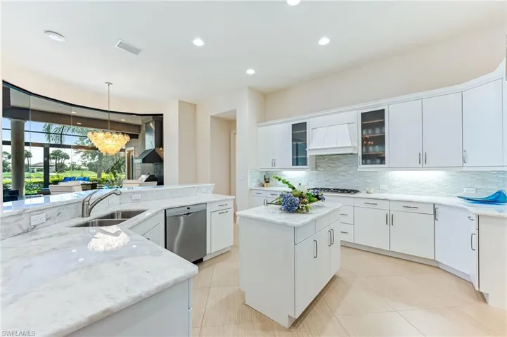 Kitchen with a center island, glass insert cabinets, hanging light fixtures, decorative backsplash, and white cabinetry