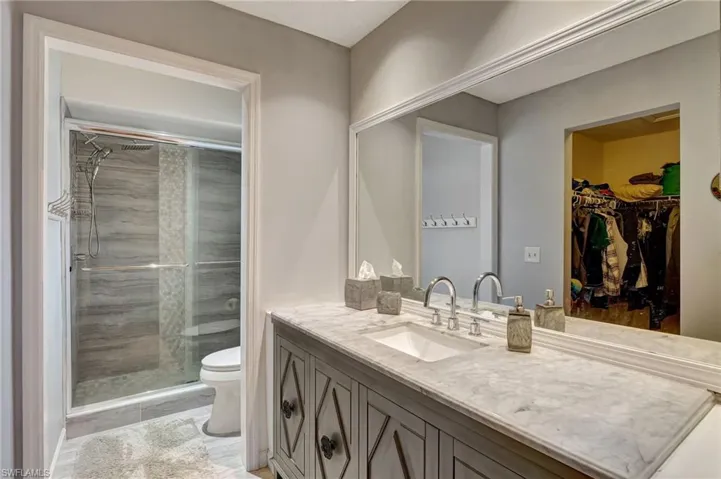 Bathroom with toilet, vanity, and a shower with shower door
