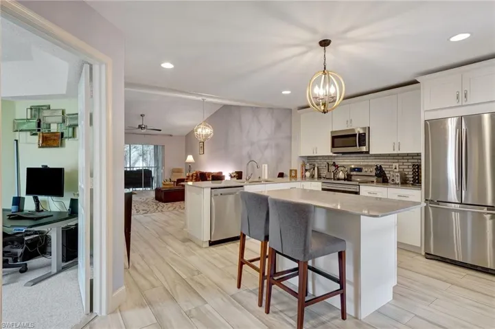 Kitchen with a kitchen island, stainless steel appliances, kitchen peninsula, and white cabinetry