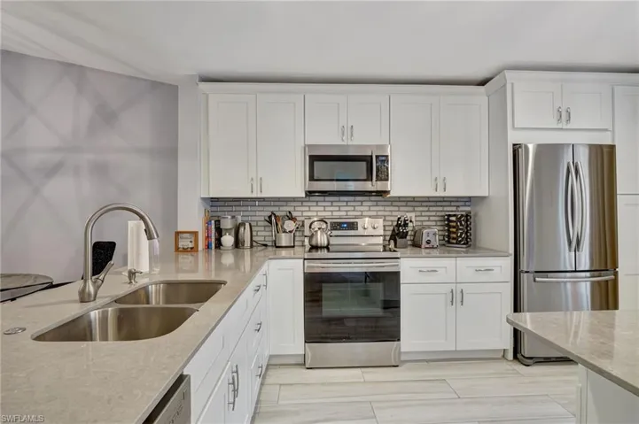 Kitchen with sink, white cabinetry and light quartz counters