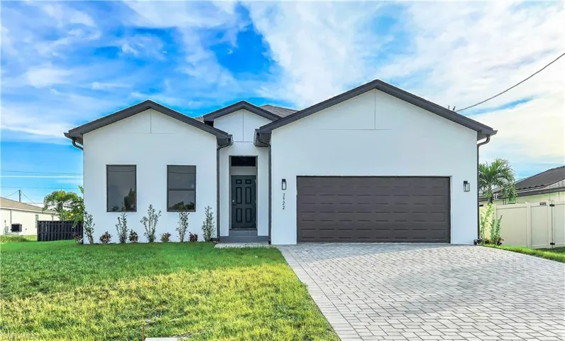 View of front of house with decorative driveway, a garage, and stucco siding