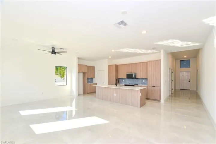 Kitchen with open floor plan, a kitchen island with sink, decorative backsplash, modern cabinets, and recessed lighting