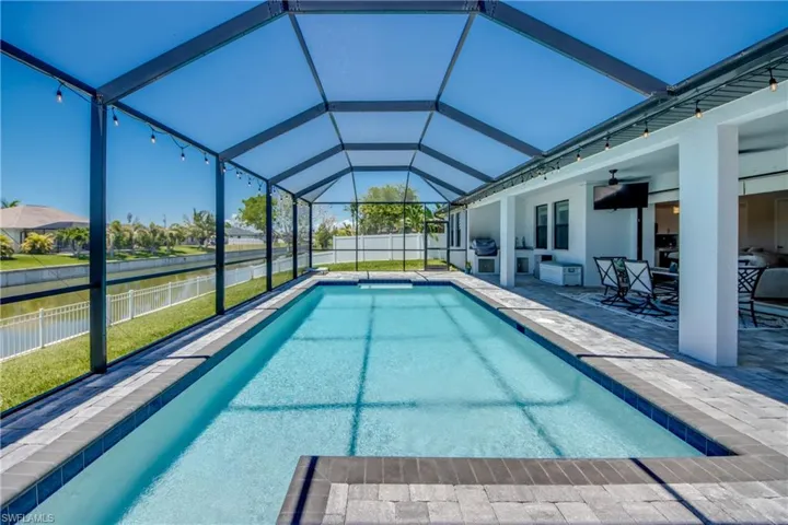 View of pool with a ceiling fan, a patio area, grilling area, a lanai, and a water view