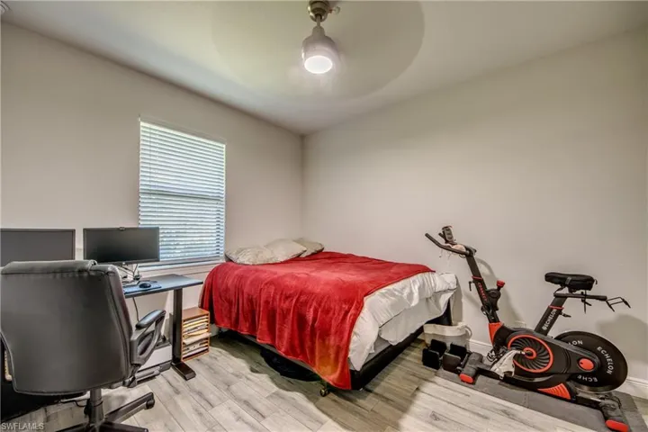 Bedroom featuring light wood-style floors, ceiling fan, and an office area