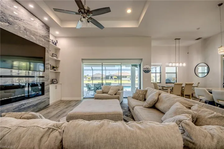 Living area with light wood-style floors, a large fireplace, a ceiling fan, recessed lighting, and built in features