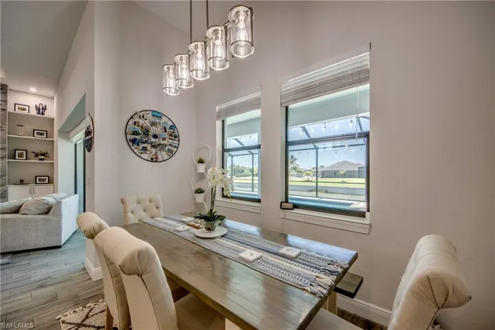 Dining room with wood finished floors, built in shelves, baseboards, a chandelier, and a high ceiling