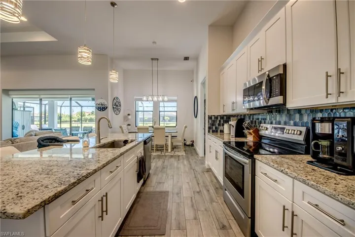 Kitchen featuring appliances with stainless steel finishes, a sink, light wood-style flooring, white cabinetry, and backsplash