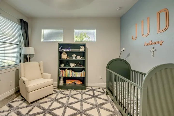 Bedroom featuring a crib, baseboards, and wood finished floors