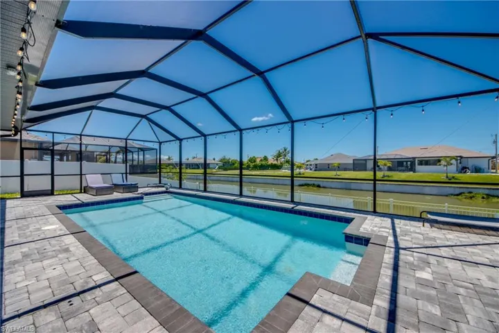 Outdoor pool with a patio area, a residential view, and glass enclosure