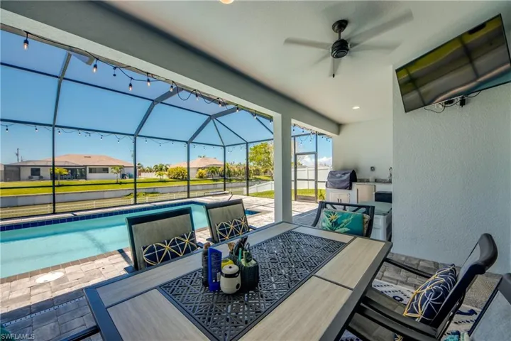 View of patio with outdoor dining area, a ceiling fan, an outdoor pool, and glass enclosure
