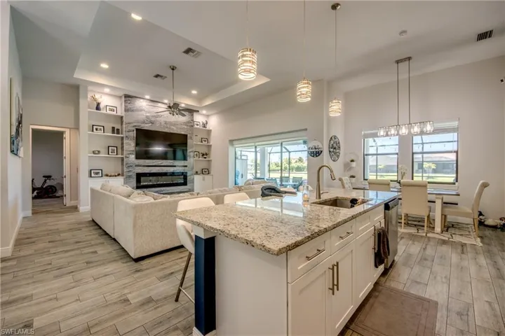 Kitchen featuring a sink, a ceiling fan, light wood-style floors, a raised ceiling, and recessed lighting