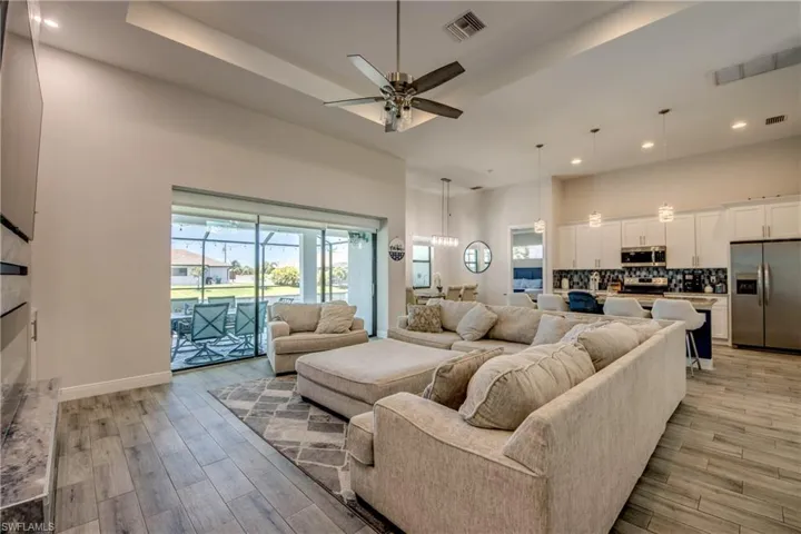 Living area featuring light wood finished floors, ceiling fan, recessed lighting, a high ceiling, and baseboards
