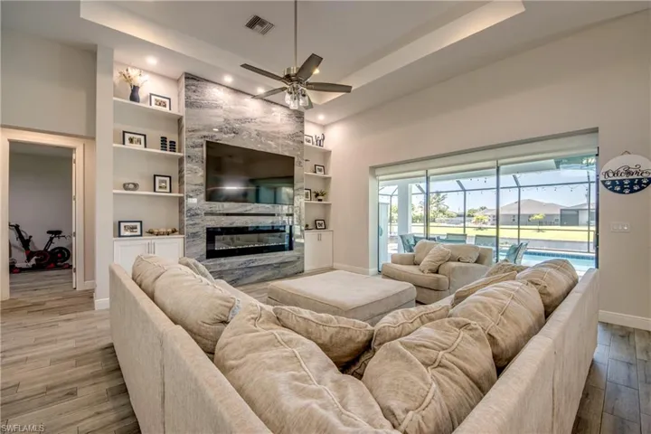 Living room with baseboards, ceiling fan, wood finished floors, a fireplace, and built in shelves