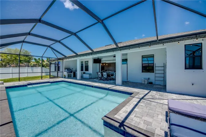 View of swimming pool featuring a patio area, ceiling fan, a lanai, and outdoor dining space