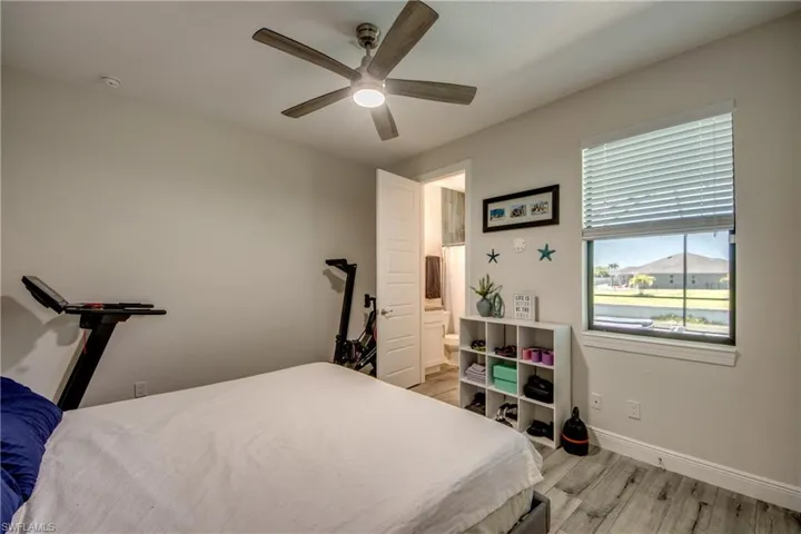 Bedroom with light wood-type flooring, baseboards, a ceiling fan, and ensuite bathroom