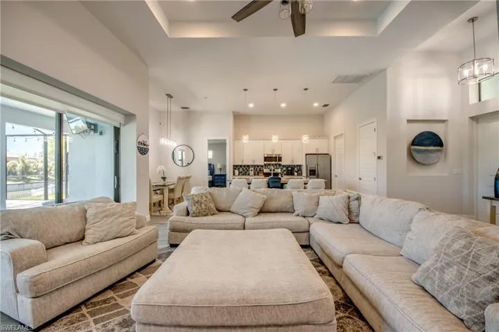 Living room with a chandelier, ceiling fan, and a tray ceiling