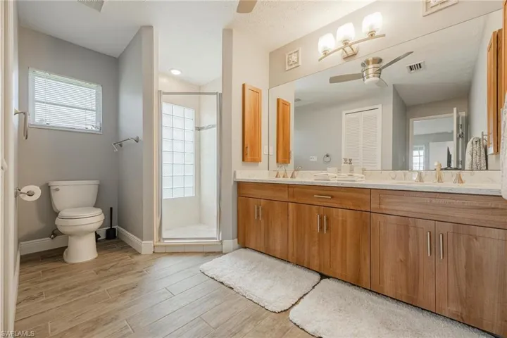 Bathroom with hardwood / wood-style floors, an enclosed shower, vanity, and toilet
