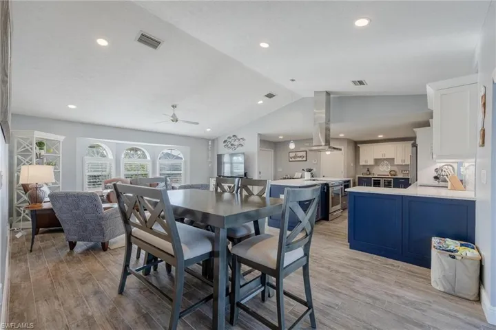 Dining area with light wood-type flooring, sink, ceiling fan, and vaulted ceiling
