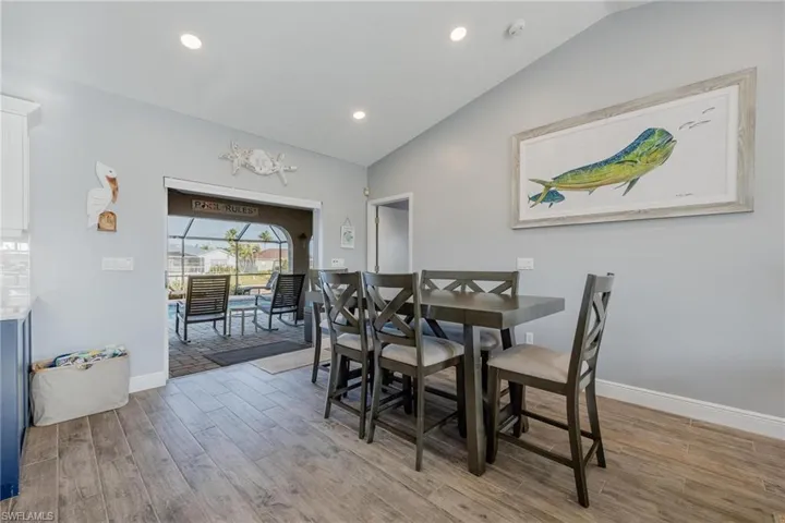 Dining space with light hardwood / wood-style floors and vaulted ceiling