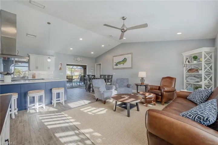 Living room with light wood-type flooring, ceiling fan, and vaulted ceiling