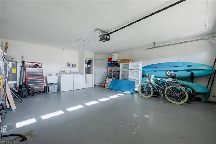 Garage featuring a garage door opener, washing machine and clothes dryer, and electric water heater
