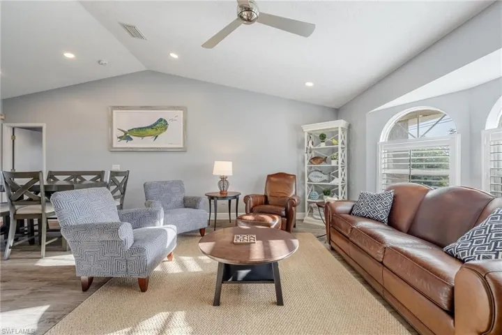 Living room with light wood-type flooring, ceiling fan, and vaulted ceiling