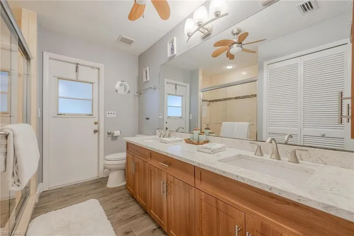 Bathroom with vanity, wood-type flooring, a textured ceiling, a shower with shower door, and toilet