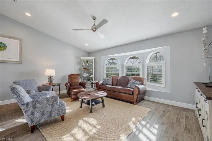 Living room with ceiling fan, light hardwood / wood-style flooring, and vaulted ceiling