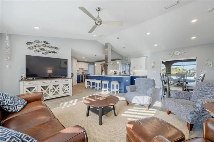 Living room with ceiling fan, lofted ceiling, and light hardwood / wood-style floors