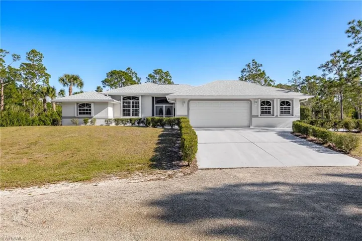 View of front of home featuring driveway, stucco siding, an attached garage, and a front yard